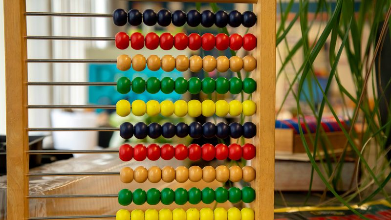 A wooden abacus with ten rows of coloured beads, each row counted across to one side