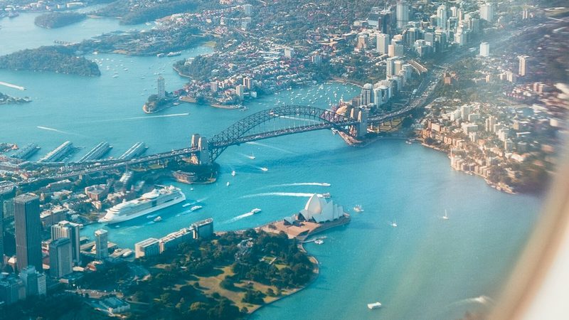 Sydney Harbour seen from a plane window, bridge and city spread below